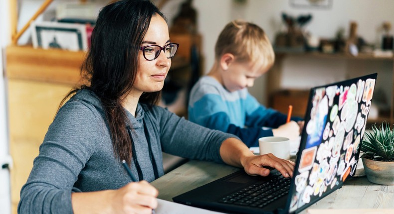 A mom works from home with her son beside her.ilona titova/Getty Images