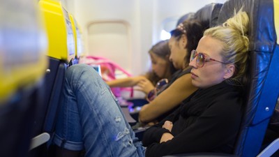 Tired lady napping on airplane.