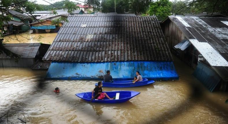 People navigate floodwaters by boat after heavy rains in Sungai Kolok district in the southern Thai province of Narathiwat on January 2, 2017