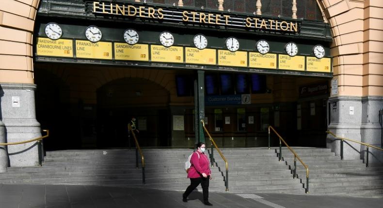 A woman walks out of a near-deserted Flinders Street Station in Melbourne after the state announced new restrictions to contain coronavirus