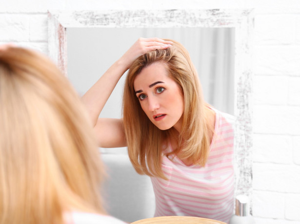 Kobieta przed lustrem ogląda włosy.