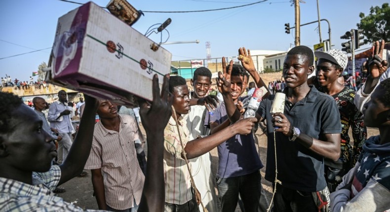 Young Sudanese protesters mimic journalists -- complete with a cardboard mocked up camera and a plastic bottle to represent a microphone -- to poke fun at state TV for failing to cover demonstrations