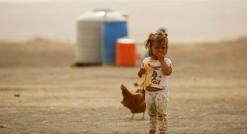 A displaced child, who fled from the Islamic State group bastion of Raqa, stands outside as she eats a loaf of bread in a camp for displaced near the town of Al-Karamah, 26 kilometres from Raqa, on May 10, 2017