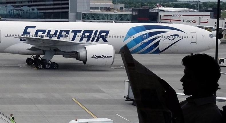 A passenger reads a newspaper at a departure hall of London's Heathrow terminal as an EgyptAir plane taxis on the tarmac of the airport May 20, 2016. 