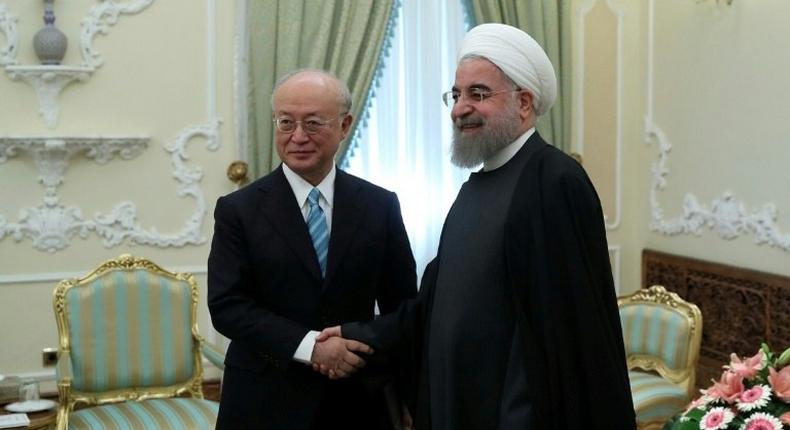 Iranian President Hassan Rouhani (R) greets Yukiya Amano (L), Director General of the International Atomic Energy Agency (IAEA) on December 18, 2016