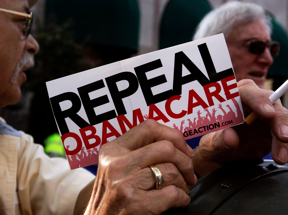 A small group of demonstrators stand outside of the HIlton Hotel and Suites prior to former South Carolina Senator Jim DeMint, president of the The Heritage Foundation, speaking at a "Defund Obamacare Tour" rally in Indianapolis August 26, 2013.