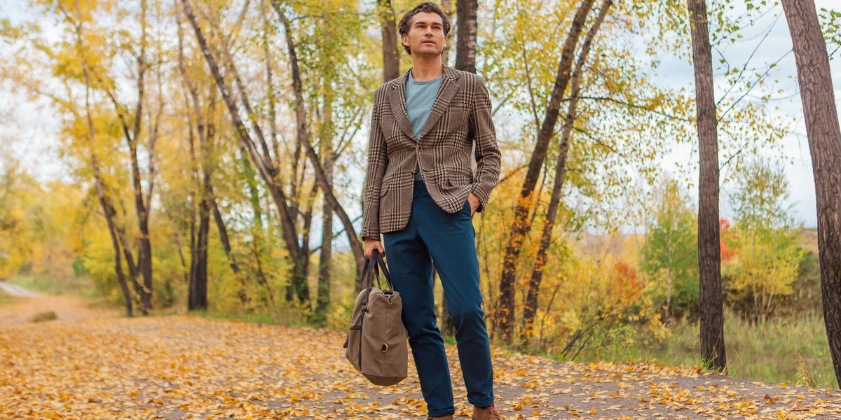 Tall handsome man with a bag on the autumn alley