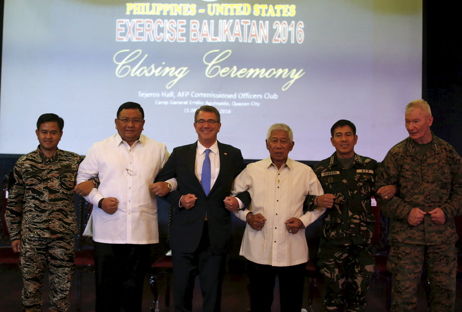 US Defense Secretary Ash Carter, third from left, and other Philippine government and military officials link arms during the closing ceremony of a US-Philippine military exercise dubbed "Balikatan," or "shoulder to shoulder," at Camp Aguinaldo in Quezon City, Metro Manila, April 15, 2016.