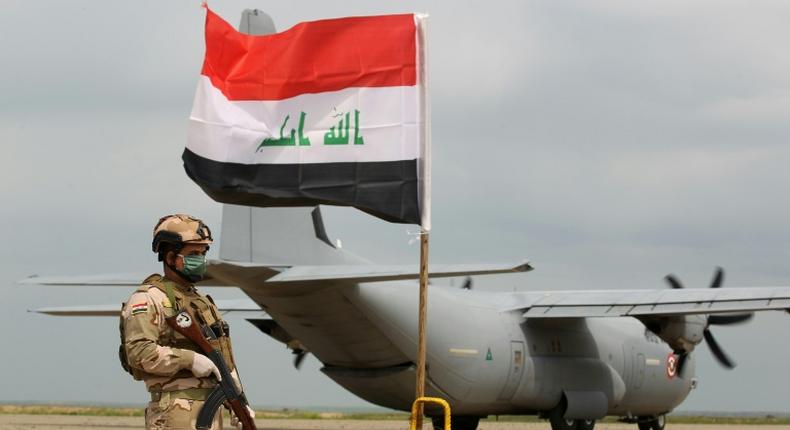 An Iraqi soldier stands guard in front of a US military air carrier at the Qayyarah air base, near Mosul in northern Iraq, on March 26, 2020. The US says it will reduce troops in the country over coming months