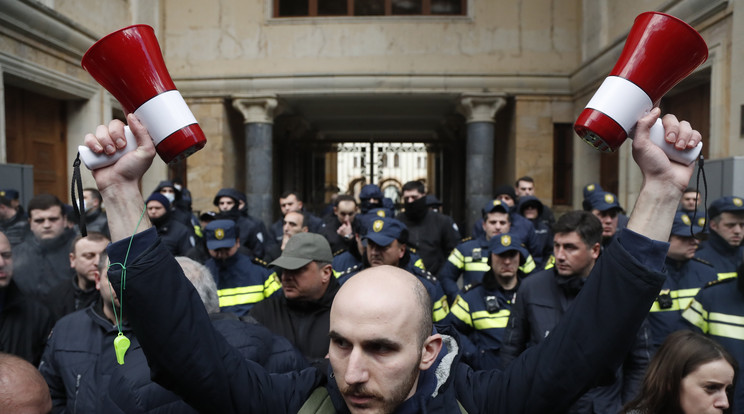 Megafonokat tart fel egy tüntető a külföldi ügynökökről szóló törvény elleni tiltakozáson a parlament épületénél Tbilisziben