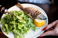 Grilled whole sea bream served with rocket salad and lemon