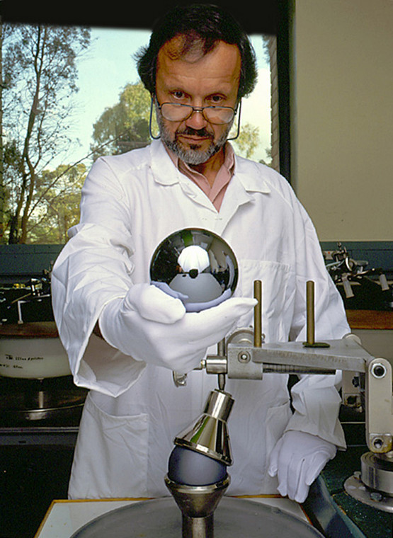 Australijski optyk Achim Leistner  trzymający w dłoni krzemową kulę