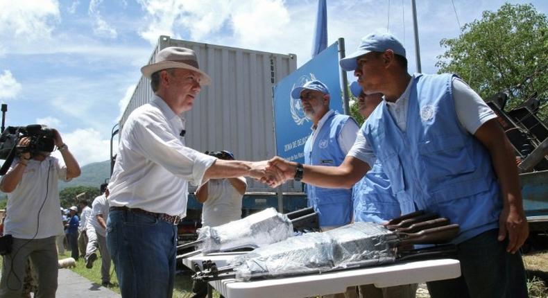 Colombian President Juan Manuel Santos shakes hands with a UN observer before closing the last container with weapons surrendered by the Revolutionary Armed Forces of Colombia (FARC) in a ceremony that brought the country's 50 year war to a final end