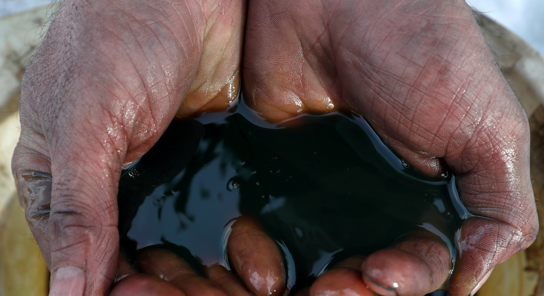 FILE PHOTO: An employee demonstrates a sample of crude oil in the Yarakta Oil Field, owned by Irkutsk Oil Company (INK), in Irkutsk Region, Russia in this picture illustration taken March 11, 2019. REUTERS/Vasily Fedosenko/Illustration/File Photo