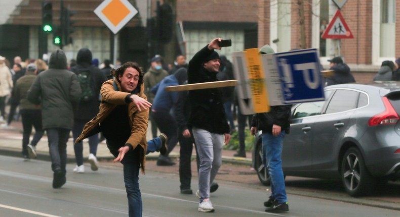 A man throws a sign at the police in a protest against coronavirus lockdowns in Amsterdam, Netherlands January 24, 2021.