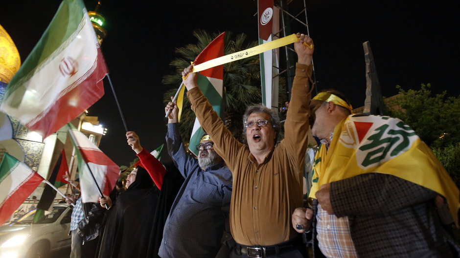 Ludzie trzymają irańskie i palestyńskie flagi podczas antyizraelskiego wiecu. Teheran, 14 kwietnia 2024 r.