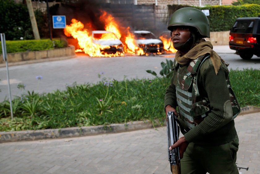 A policeman runs past burning cars at the scene where explosions and gunshots were heard at the Dusi