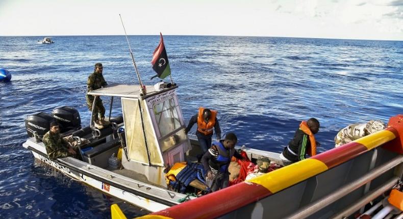 Libyan coastguards help migrants board a rescue ship run by Maltese NGO Moas and the Italian Red Cross, during a rescue operation, on November 4, 2016