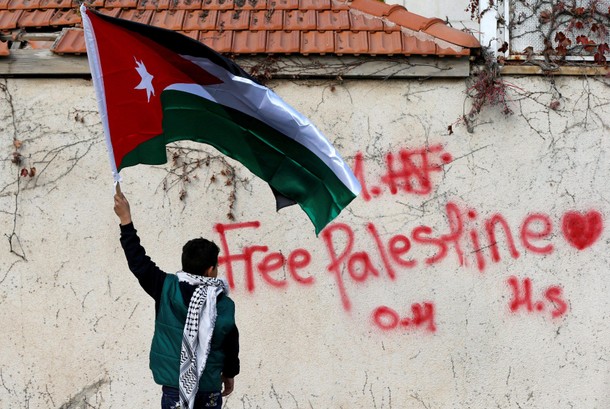 A boy holds the Jordanian national flag during a protest near the U.S. Embassy in Amman