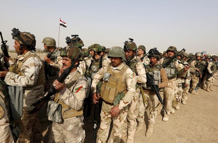 Iraqi security forces wait at an army base in Baghdad for vehicles traveling to Mosul to fight ISIS militants.