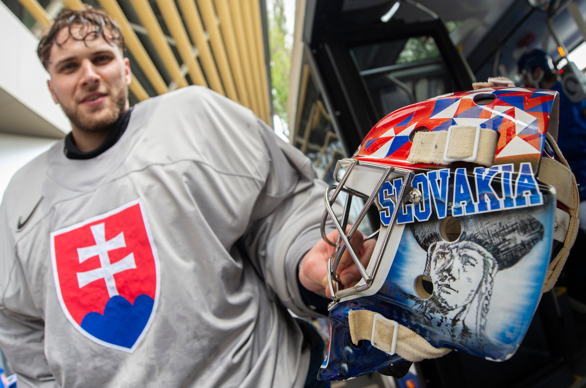 Slovenský hokejový reprezentant, brankár Samuel Hlavaj ukazuje svoju helmu, na ktorej má zobrazeného Juraja Jánošíka po tréningu.