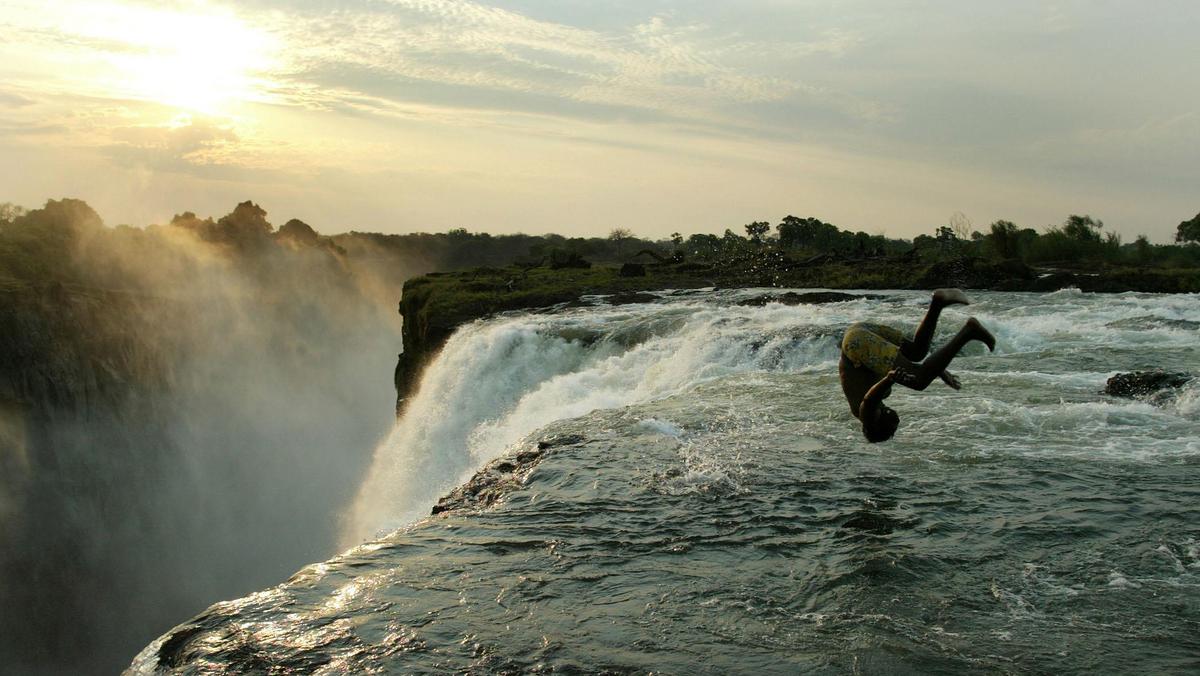 A Zambian man somersaults into a pool at the edge of the 110 metre high main falls of the Victoria F