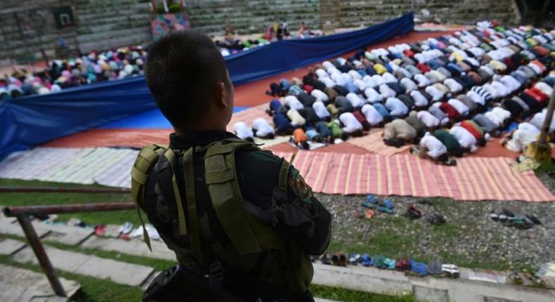 A member of the police special action force stands guard as Muslims, who fled the conflict in Marawi, pray during Eid al-Fitr in Iligan City on the southern island of Mindanao