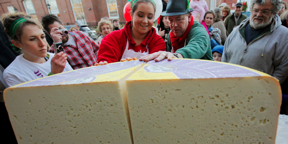 Peter Lovis, proprietor of the Concord Cheese Shop, and Brie Hurd quarter what was a 400-pound wheel of Crucolo cheese outside the shop in Concord, Massachusetts, on December 1, 2011.