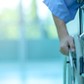 Asian disabled man is sitting in a wheelchair. He holds his hands on the wheel. Nearby are his colleagues, Medical equipment.