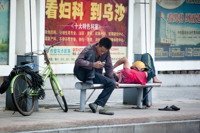 Pracownicy fabryki w mieście Dongguan czekają na autobus do pracy