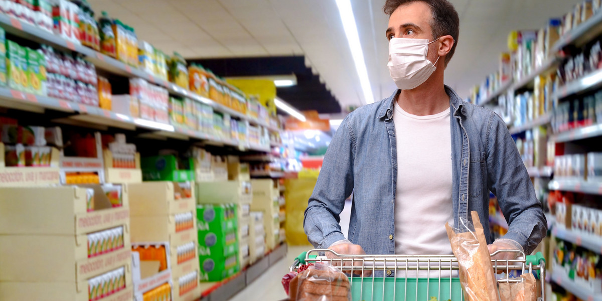 man in mask and protective gloves buying food in shop at coronavirus epidemic