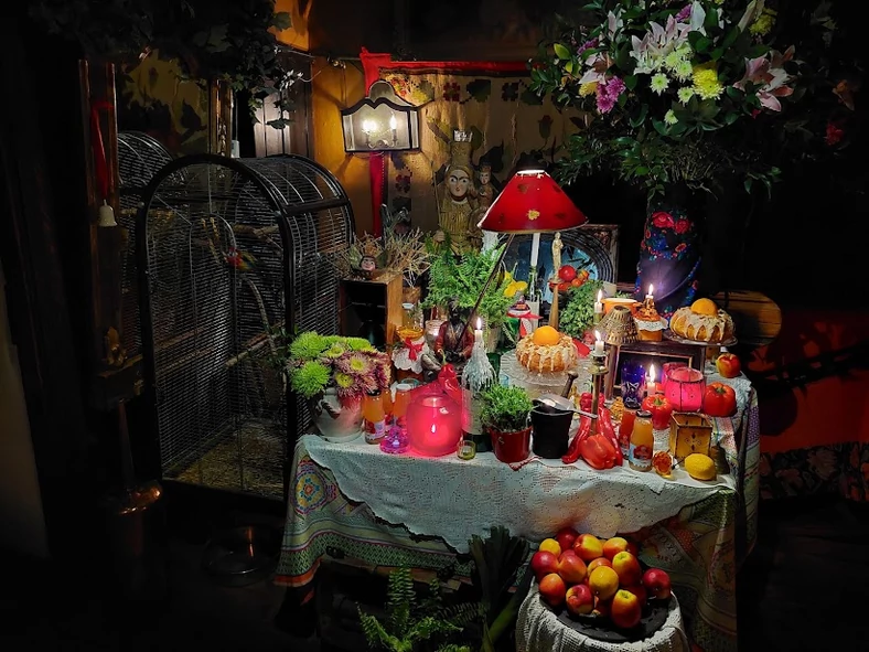 Ołtarzyk z przetworami, owocami, świecami i papużką po lewej