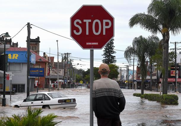 A local resident watches as floodwaters enter the main street of northern New South Wales town of Li
