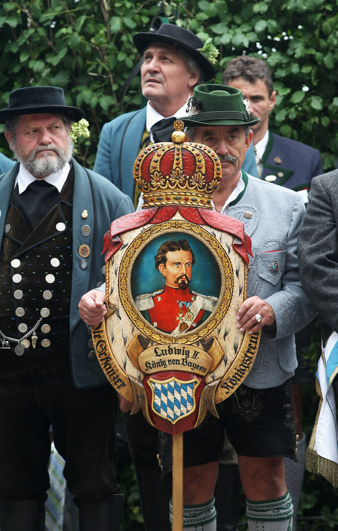 Uczestnicy mszy z okazji obchodów 125. rocznicy śmierci Ludwika II w tradycyjnych strojach bawarskich, z portretem króla