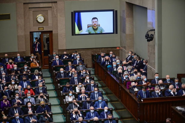 Prezydent Ukrainy Wołodymyr Zełenski (na ekranie) przemawia podczas uroczystego zgromadzenia posłów i senatorów na sali plenarnej Sejmu w Warszawie