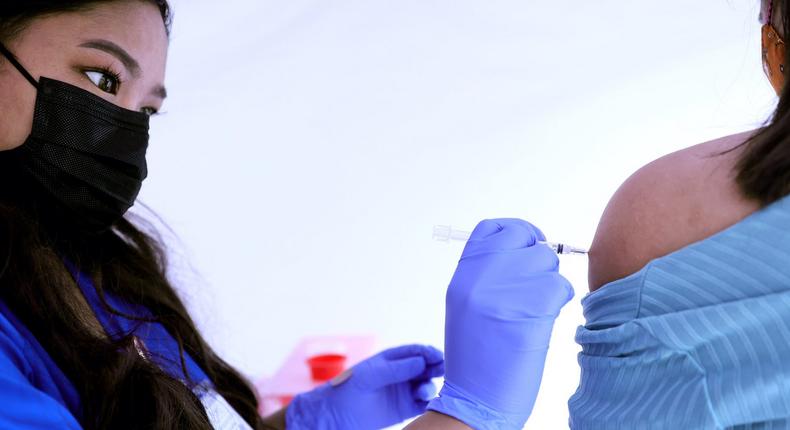 A medical assistant administers a COVID-19 vaccine dose to a woman at a clinic in Los Angeles on March 25, 2021.
