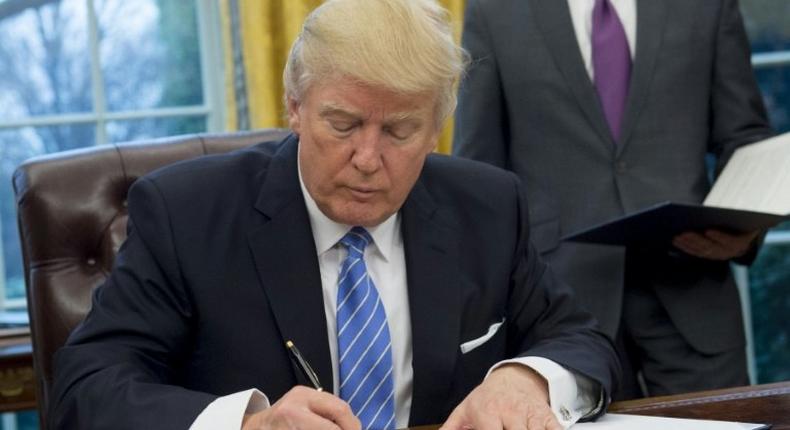 US President Donald Trump signs an executive order withdrawing the US from the Trans-Pacific Partnership in the Oval Office of the White House on January 23, 2017