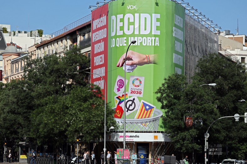 Billboard skrajnie prawicowej partii Vox z napisem "Decyduj, co się liczy". Ręka wyrzuca do kosza katalońską niepodległościową flagę "Estelada", symbole LGBT oraz feminizmu, komunizmu i ruchu squatersów "Okupa"