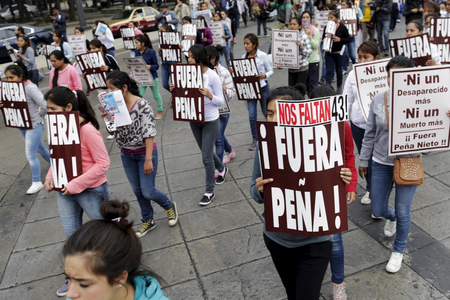 Demonstrators hold signs as they take part in a march in Mexico City to mark the one-year anniversary of the disappearance of 43 students from Mexico's Ayotzinapa College Raul Isidro Burgos, October 26, 2015.