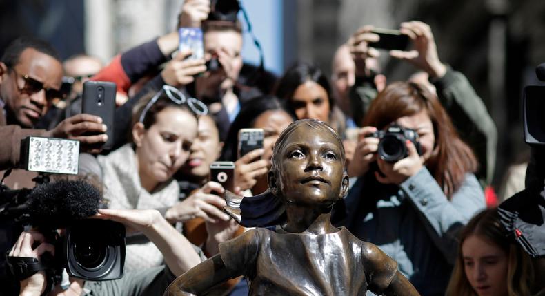 People stop to photograph the Fearless Girl statue, Wednesday, March 8, 2017, in New York.