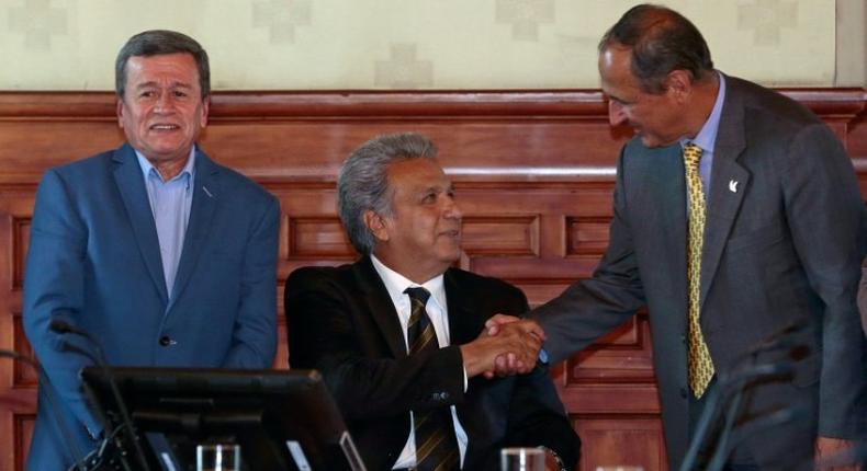 Colombia's government chief negotiator Juan Camilo Restrepo (R) shakes hands with Ecuador's President Lenin Moreno (C) as the National Liberation Army rebel group's chief negotiator, Pablo Beltran, looks on in Quito on August 28, 2017