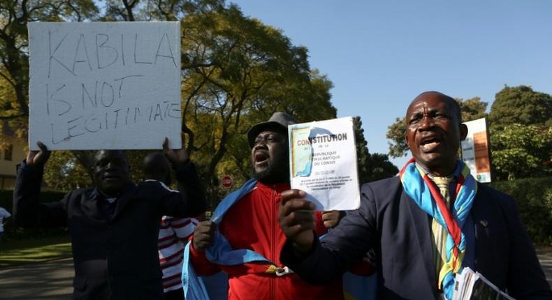 Anti-President Kabila protestors shout slogans and wave placards as they demonstrate near the entrance to a presidential guest house in Pretoria on June 24, 2017, where the President of the Democratic Republic of Congo Joseph Kabila and South African president Jacob Zuma were meeting during an official state visit by Kabila.