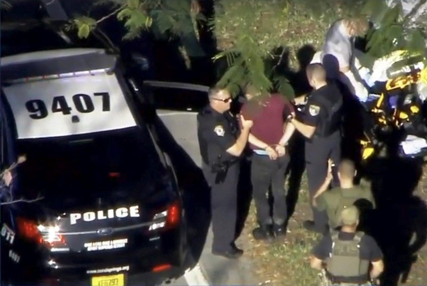 Police escort a suspect into the Broward Jail after checking him at the hospital following a shootin