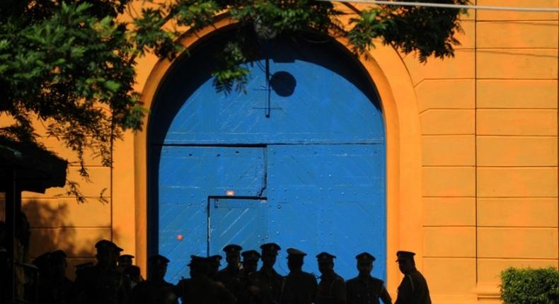 Sri Lankan policemen stand guard in front of protesters outside the main prison in Colombo on August 8, 2011