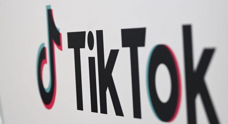 A person walks past a sign for TikTok.