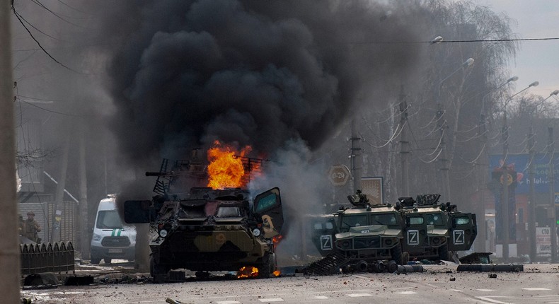 A Russian armored personnel carrier burns amid damaged and abandoned light utility vehicles after fighting in Kharkiv, Ukraine, Sunday, Feb. 27, 2022.