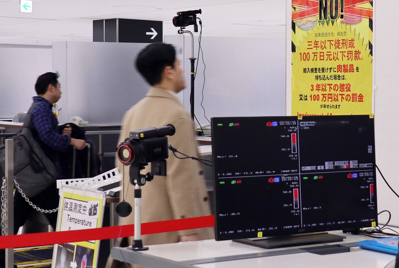Pasażerowie przechodzący przez medyczną kontrolę na japońskim lotnisku Narita