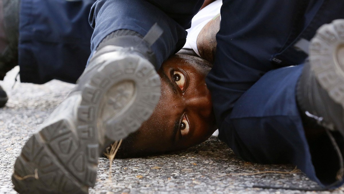 A man protesting the shooting death of Alton Sterling is detained by law enforcement near the headqu