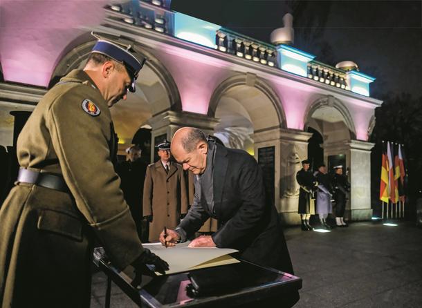 Kanclerz Olaf Scholz wpisuje się do księgi pamiątkowej po złożeniu wieńca przed Grobem Nieznanego Żołnierza w Warszawie, grudzień 2021 r.