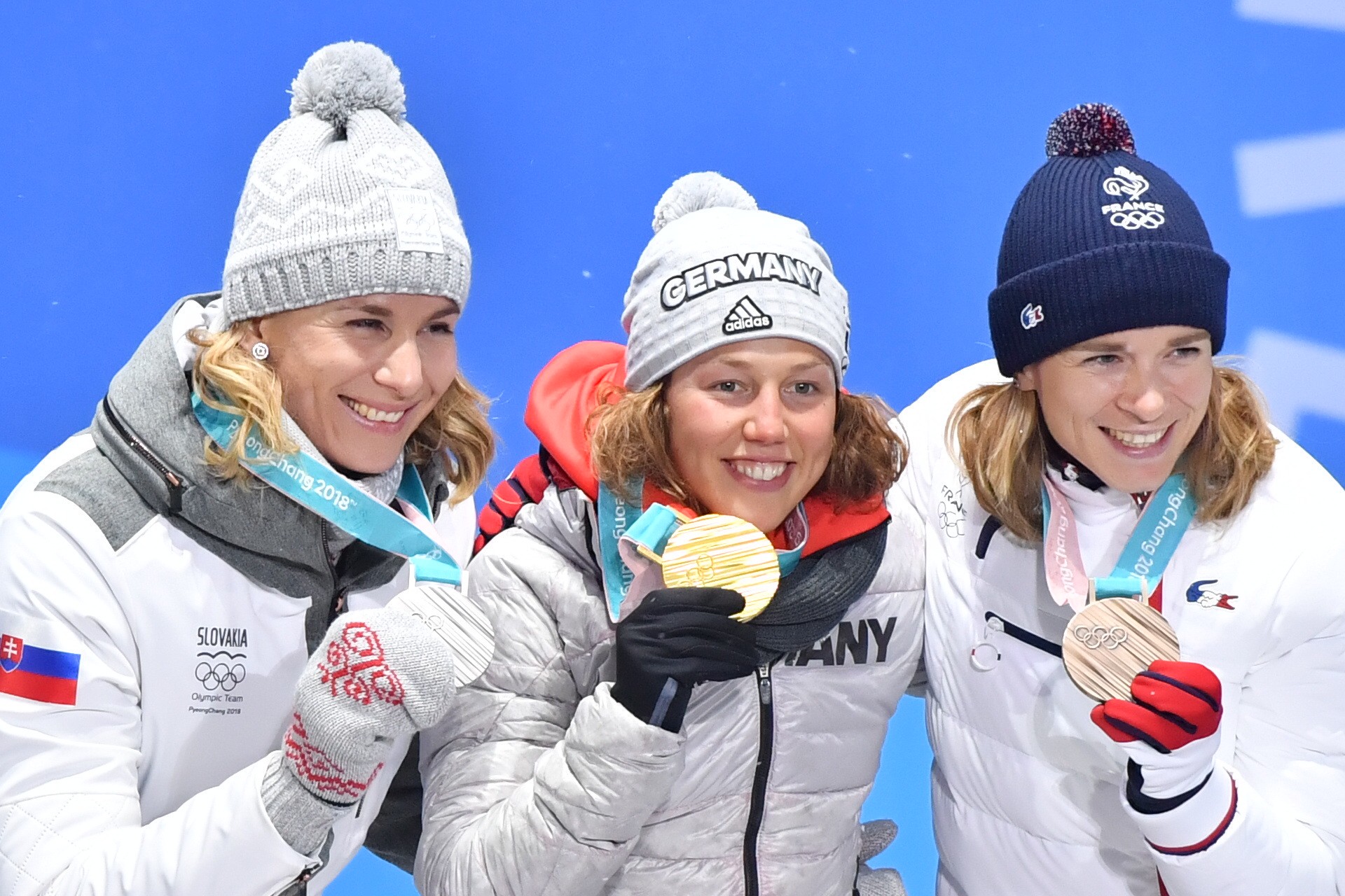 Slovenská biatlonistka Anastasia Kuzminová pózuje so striebornou medailou, ktorú získala na ZOH 2018, uprostred Nemka Laura Dahlmeierová.